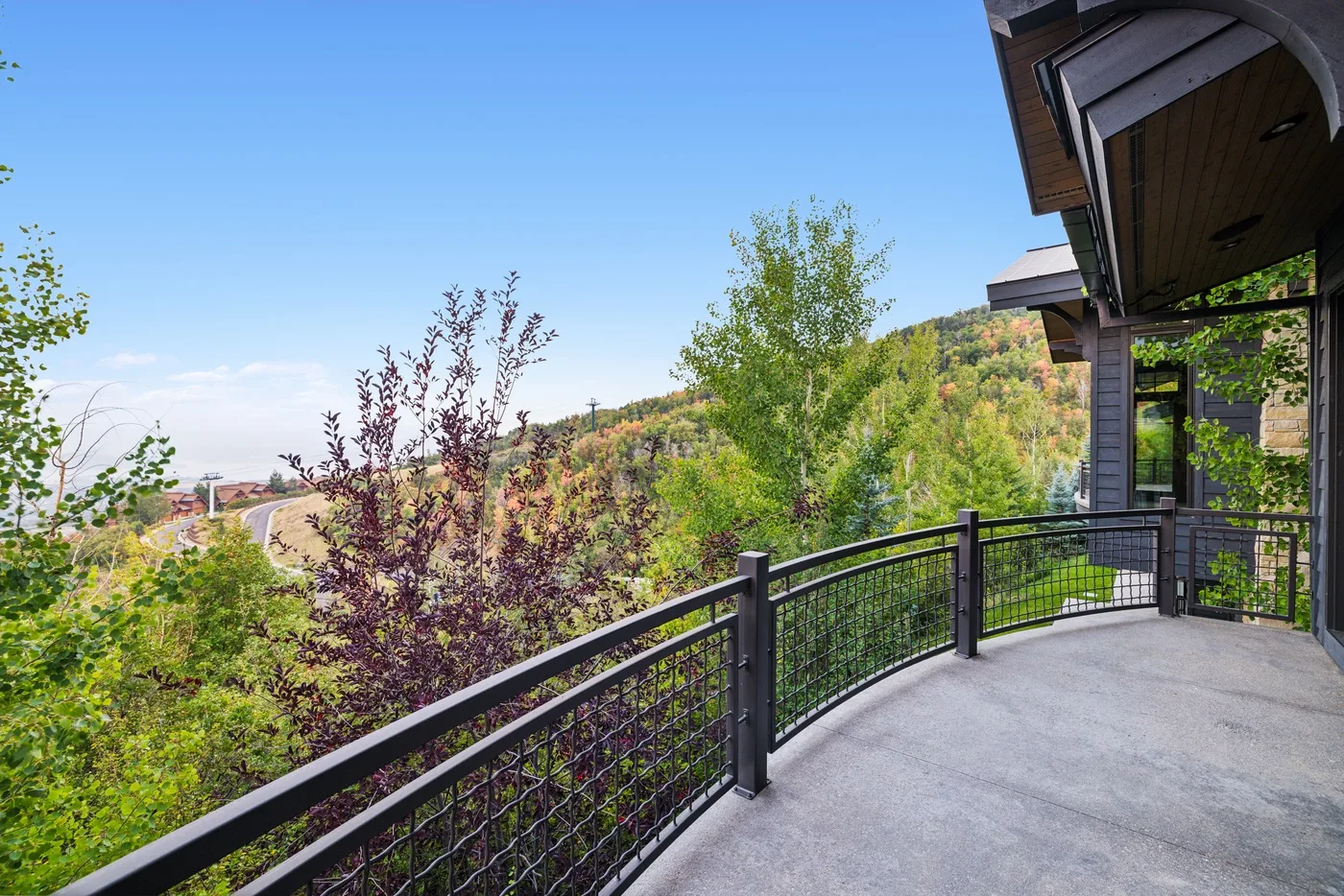 A curved outdoor balcony overlooks a green, wooded hillside.