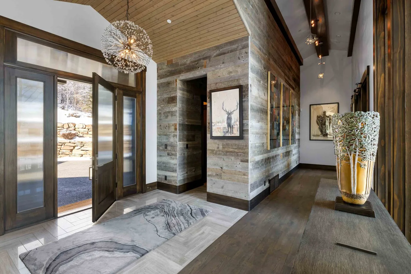 A wood-paneled entry hall with glass doors and artwork along the walls.