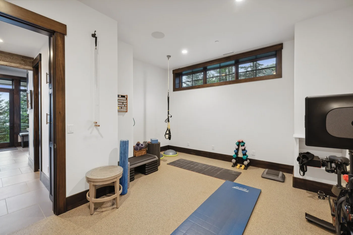 A bright exercise room with a blue mat and fitness equipment.