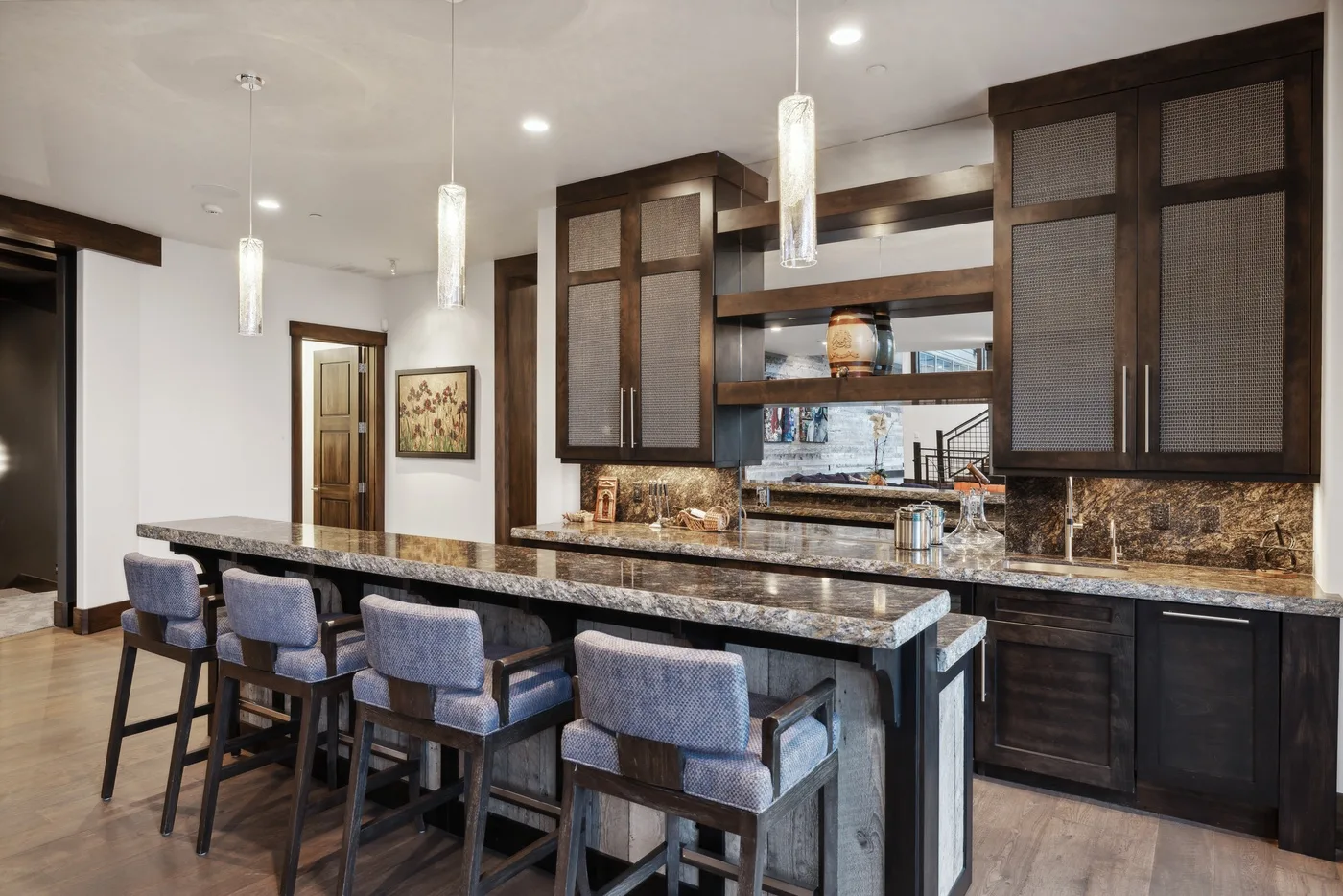 A kitchen bar with seating faces dark cabinetry and a countertop.
