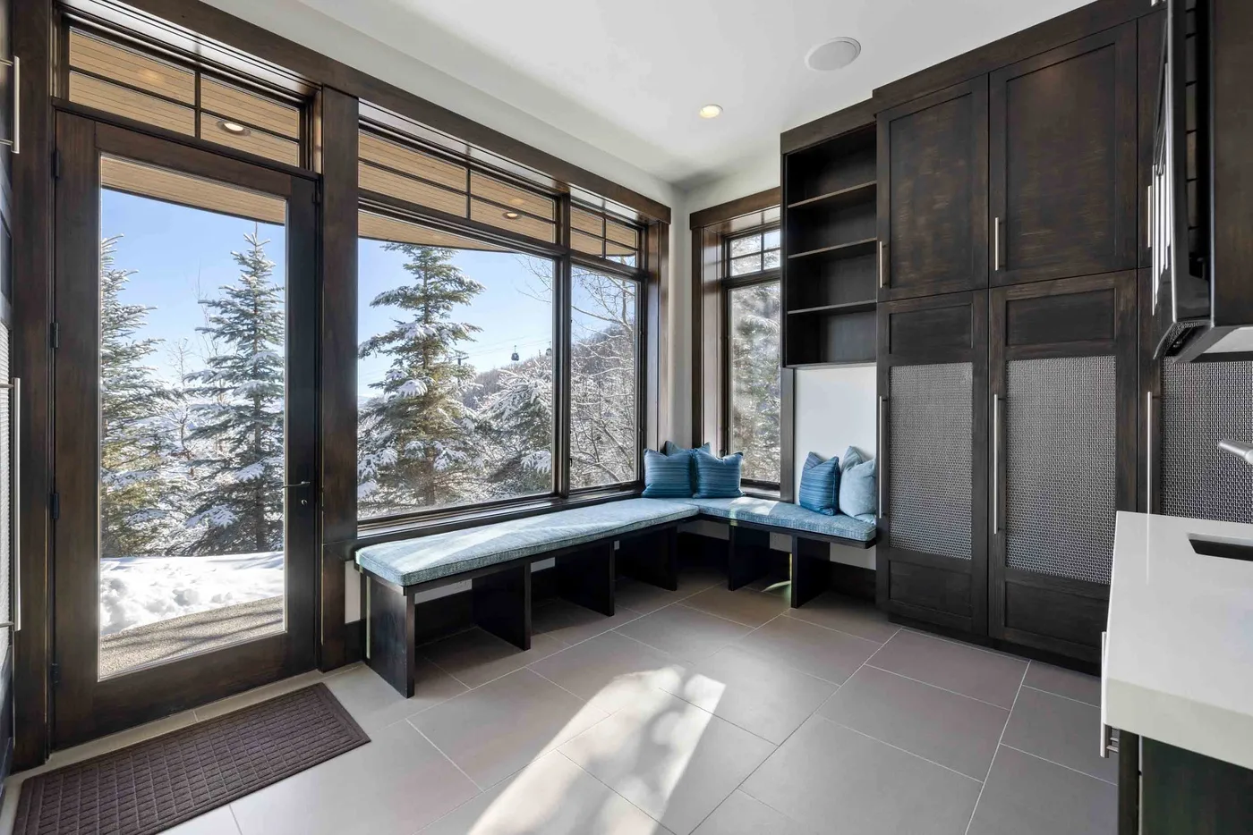 A bright window seating area overlooks snow-covered trees.