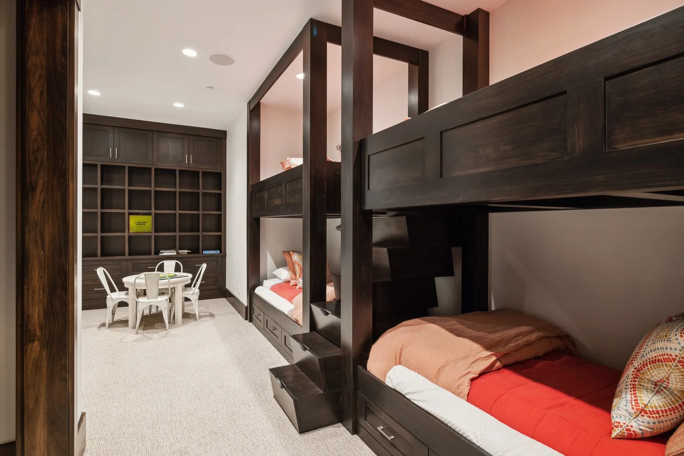 A bedroom with built-in bunk beds and a small table with chairs.