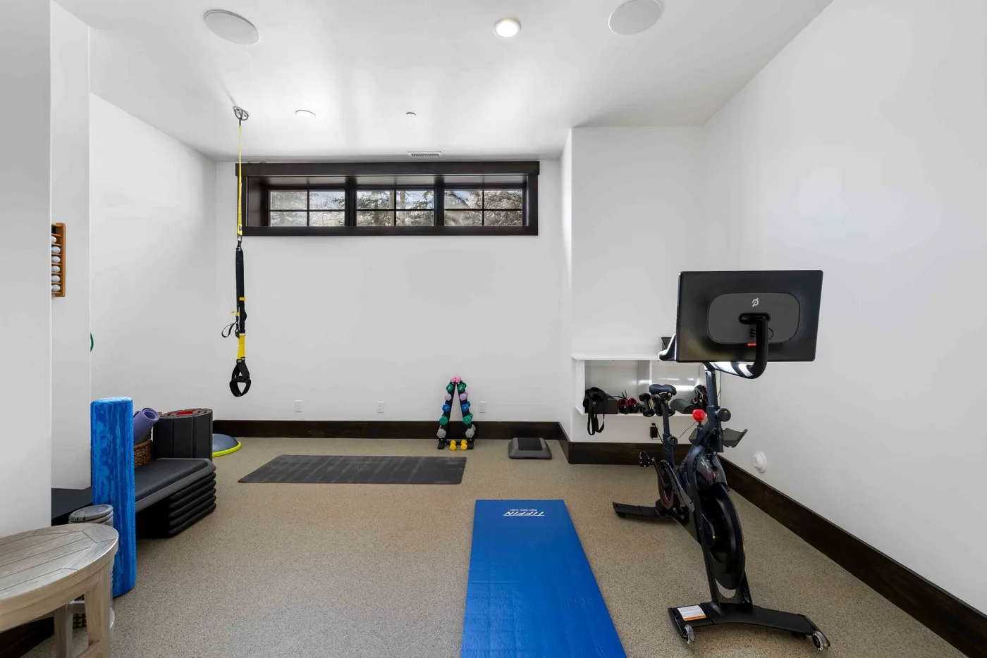 A compact exercise room with a blue mat, stationary bike, and workout equipment.