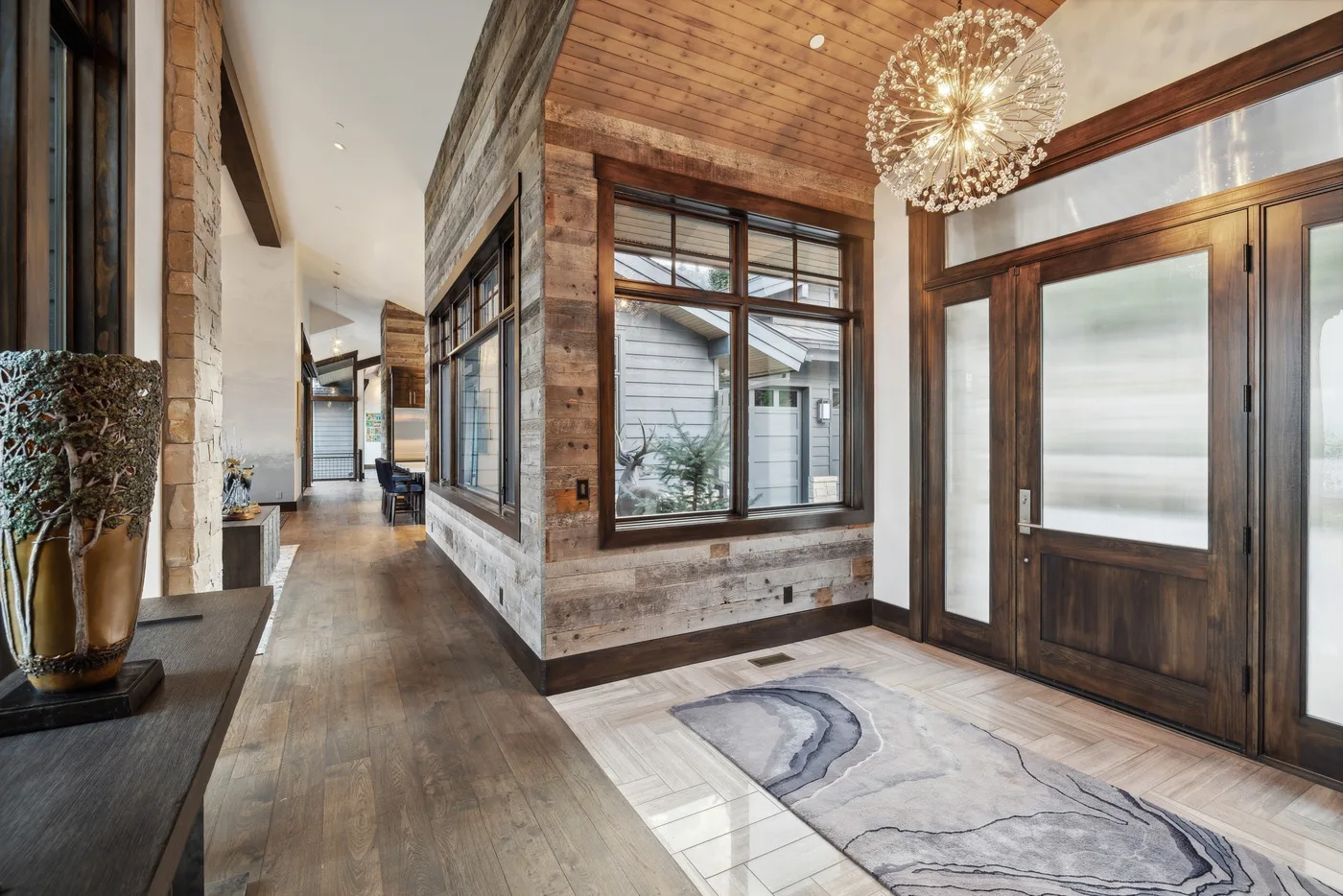 A spacious entryway with a wood ceiling, large windows, and a dark wood front door.