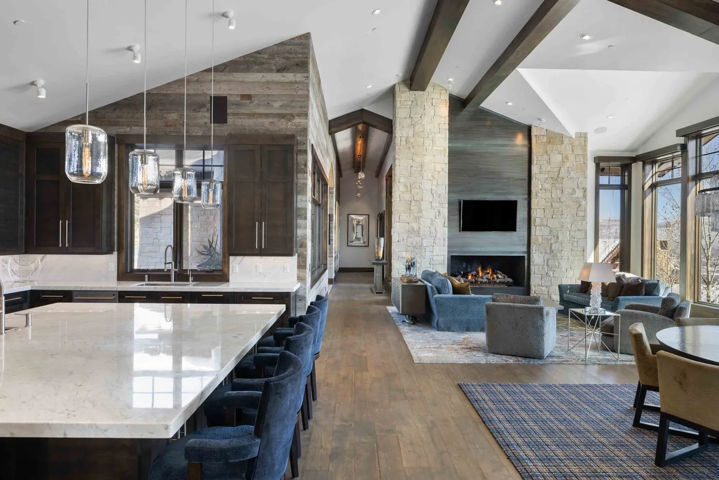 An open-plan kitchen and living area with a large island and stone fireplace.