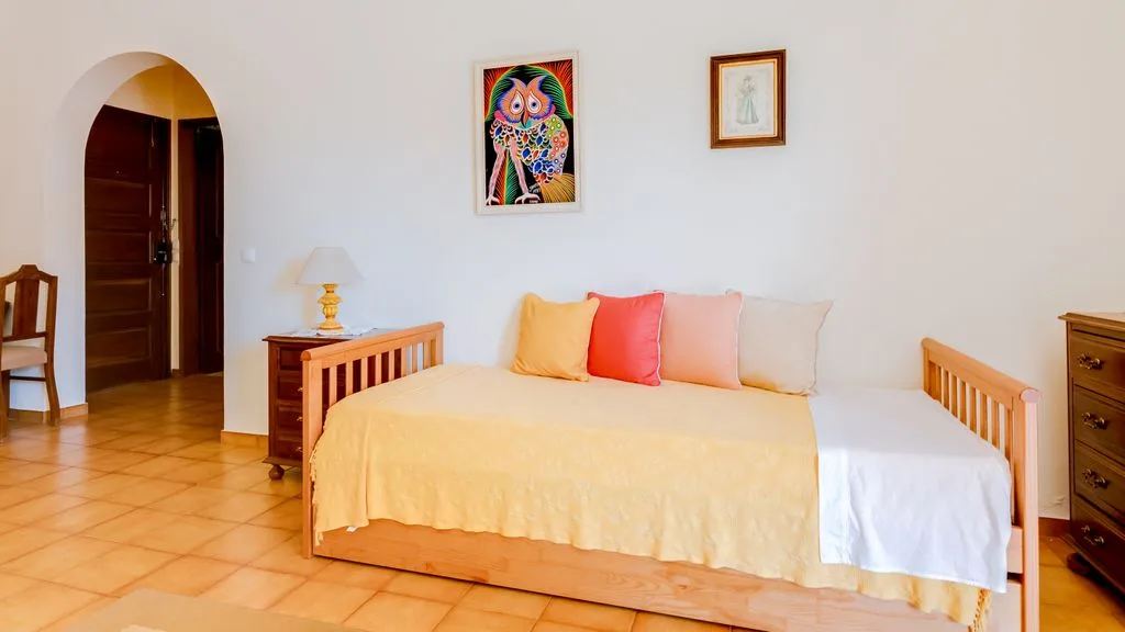 A bedroom with a daybed and colorful framed artwork on the wall.
