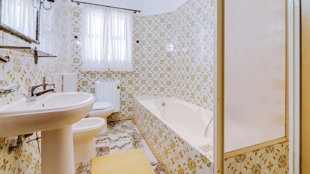 A patterned bathroom with a bathtub, sink, and toilet.