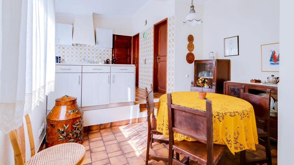 A dining area with a yellow tablecloth beside a compact kitchen.