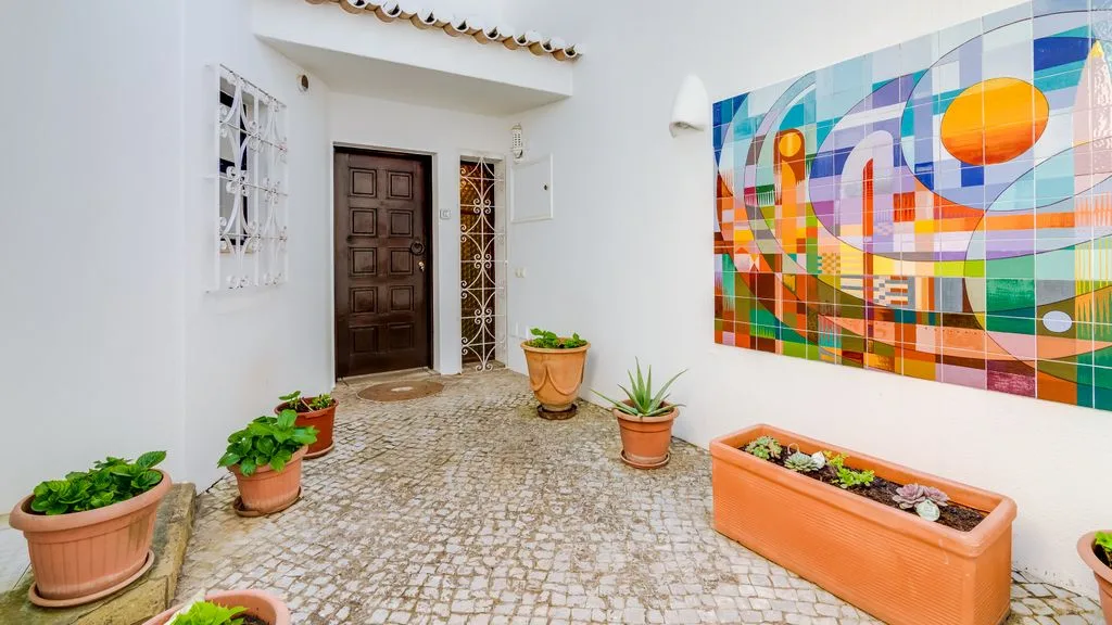 A bright entry courtyard features a dark wooden door and colorful mural.
