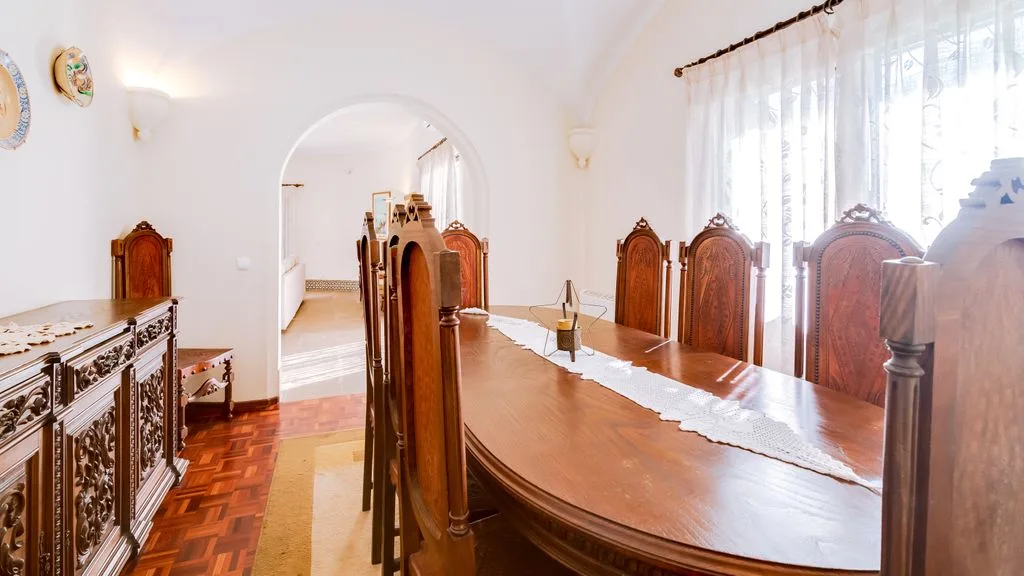 A dining room with a long wooden table and carved chairs.