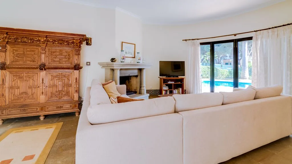 A bright living room with white seating, a fireplace, and glass doors opening to a patio.