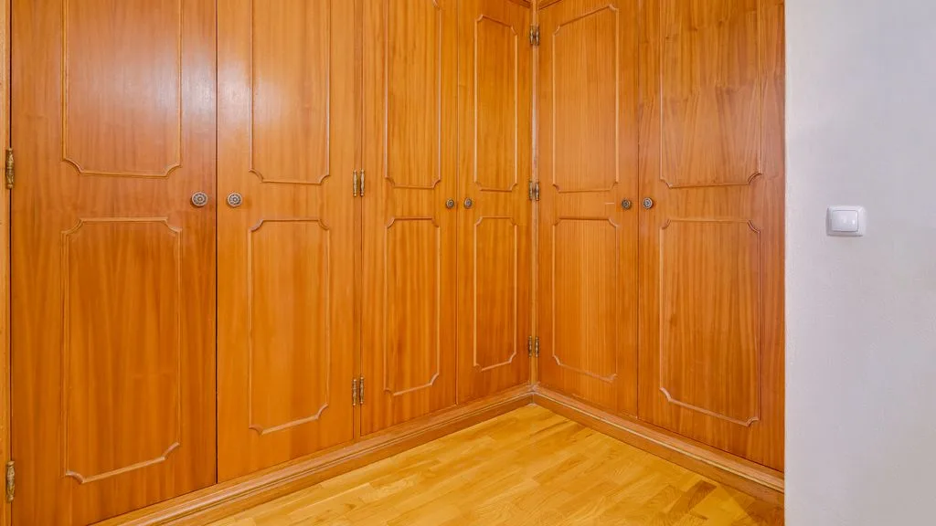 A room with a large wooden built-in wardrobe.