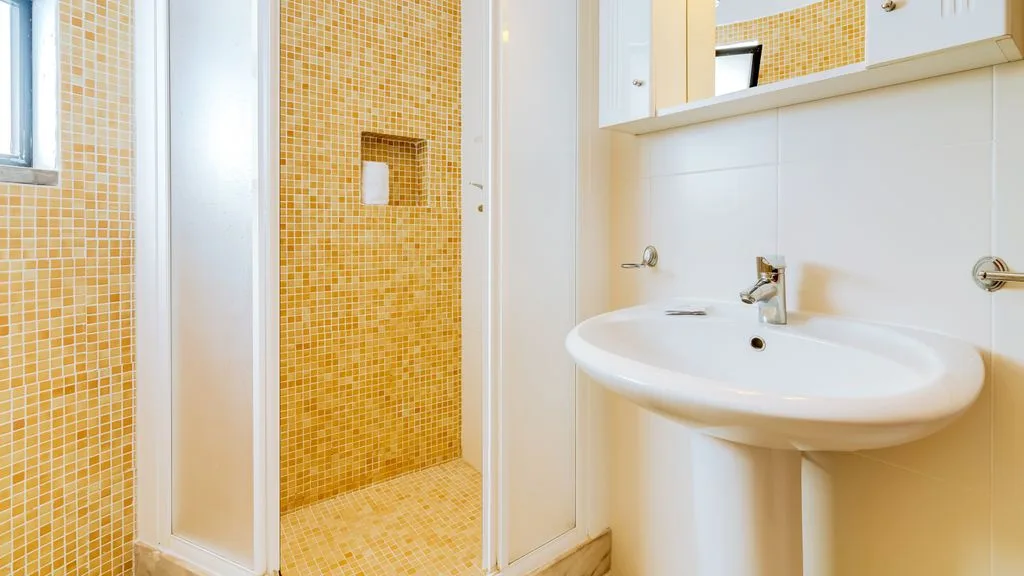 A bright bathroom with a white sink and tiled shower area.