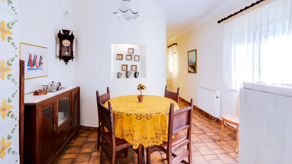A dining room with a round table covered by a yellow cloth.