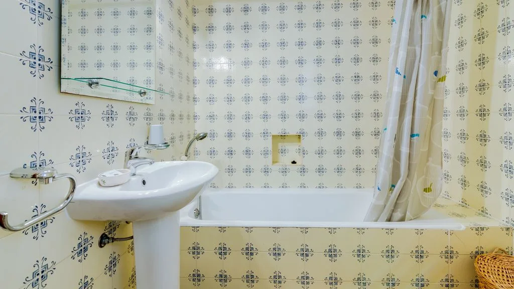 A tiled bathroom with a sink, bathtub, and shower curtain.