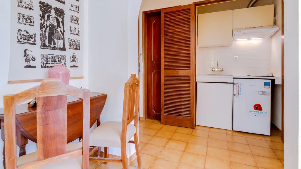 A dining area with wooden seating beside a compact kitchen.