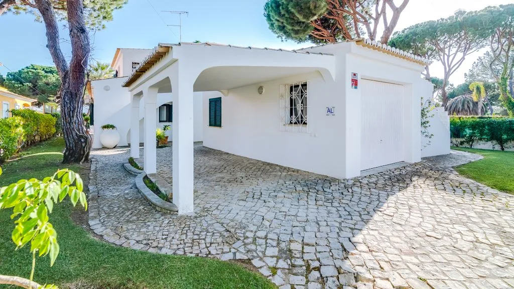 A white house with a covered entrance stands beside a cobblestone path.