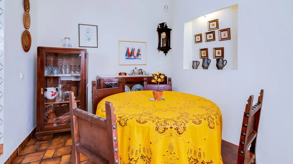 A dining room with a round table covered in a yellow cloth.