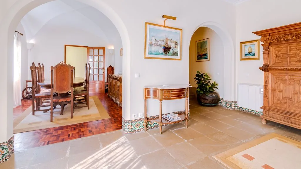 An interior hallway with arched openings, a console table, and wooden furnishings.