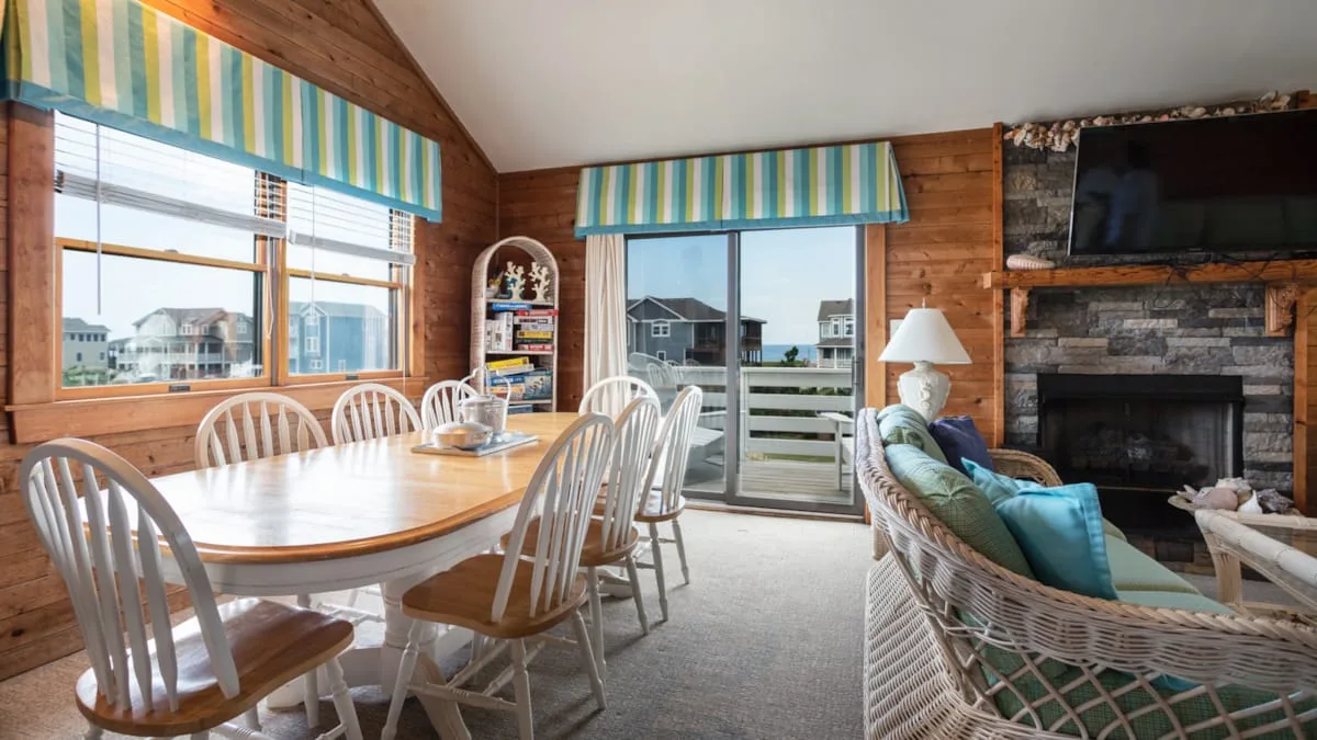 A wood-paneled living and dining area with a table, seating, and a fireplace.
