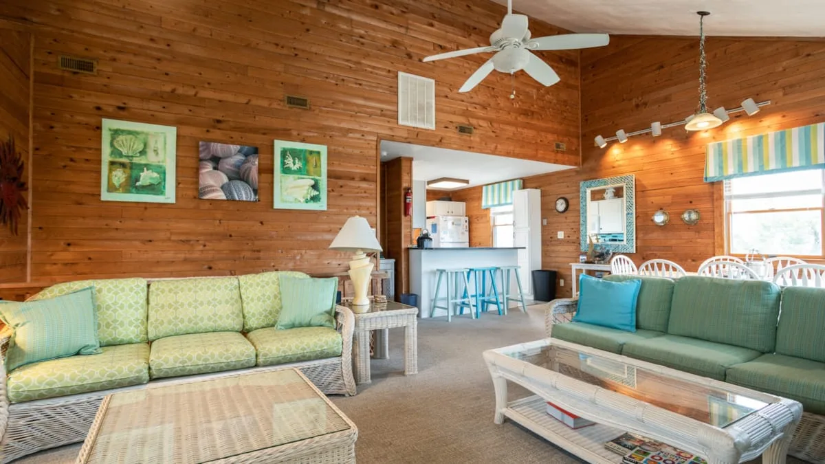 A wood-paneled living room with sofas and a glass-topped coffee table.