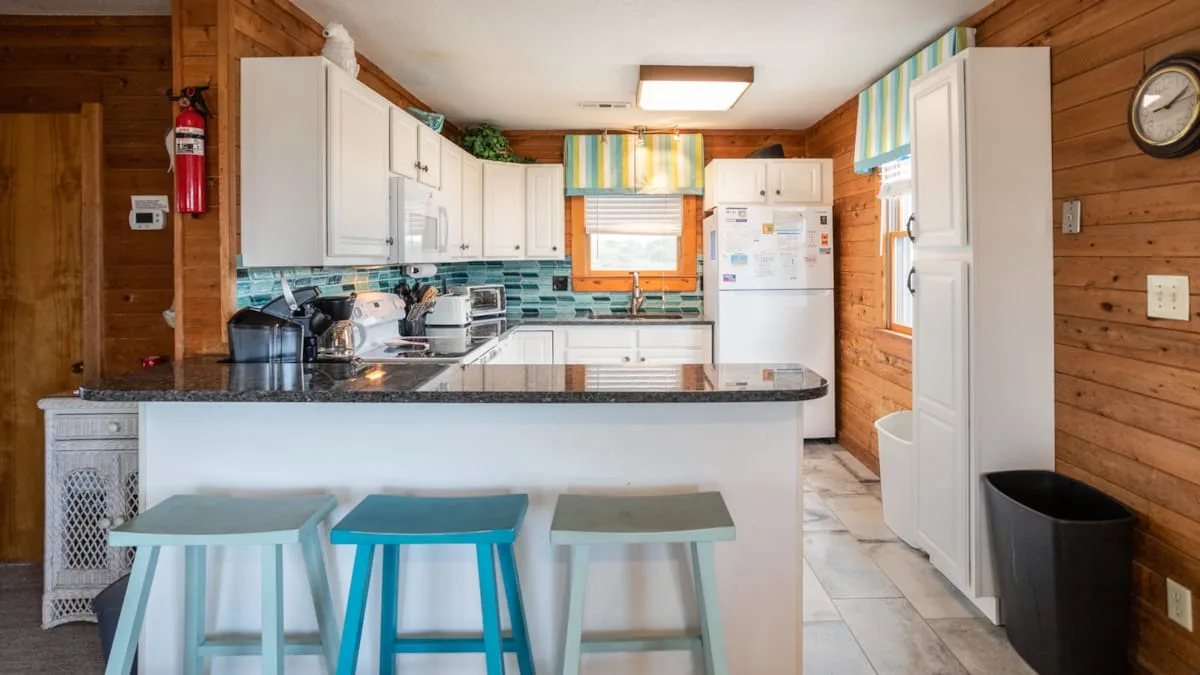 A kitchen with a breakfast counter and colorful window valances.