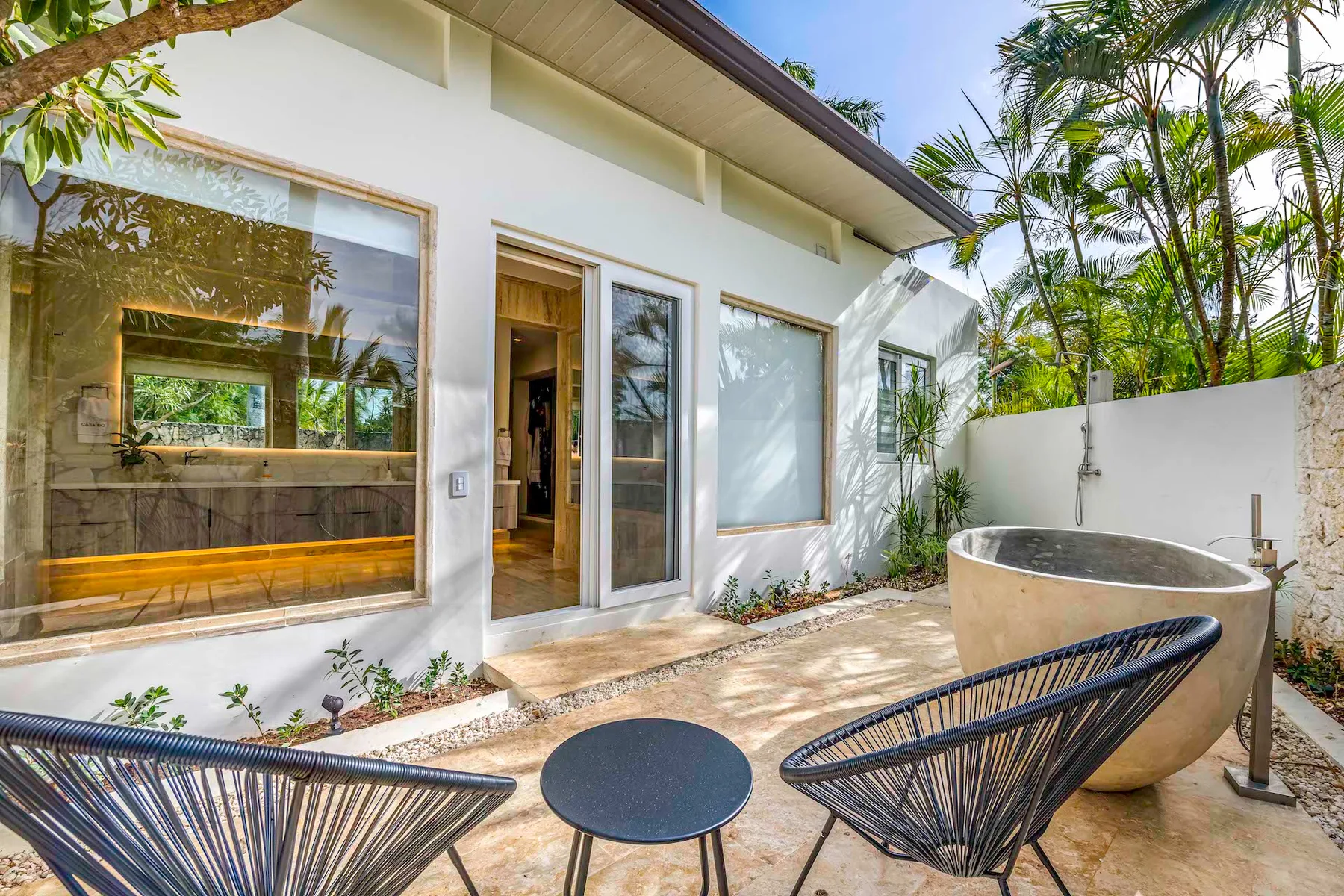 Un patio exterior con asientos y una gran tina redonda junto a la casa.