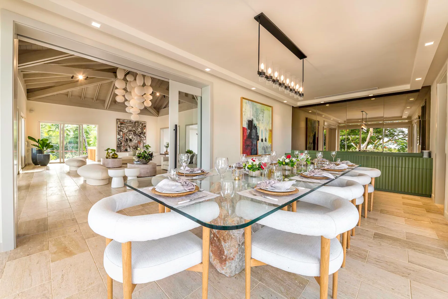 Un comedor luminoso con una mesa de vidrio preparada para comer y asientos blancos.