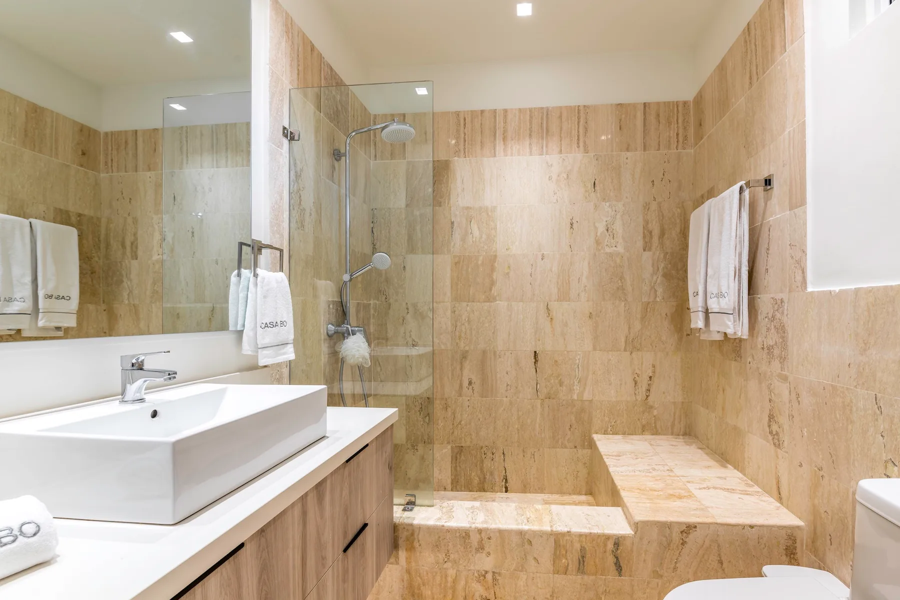 Un baño alicatado con lavabo, ducha y banco integrado.