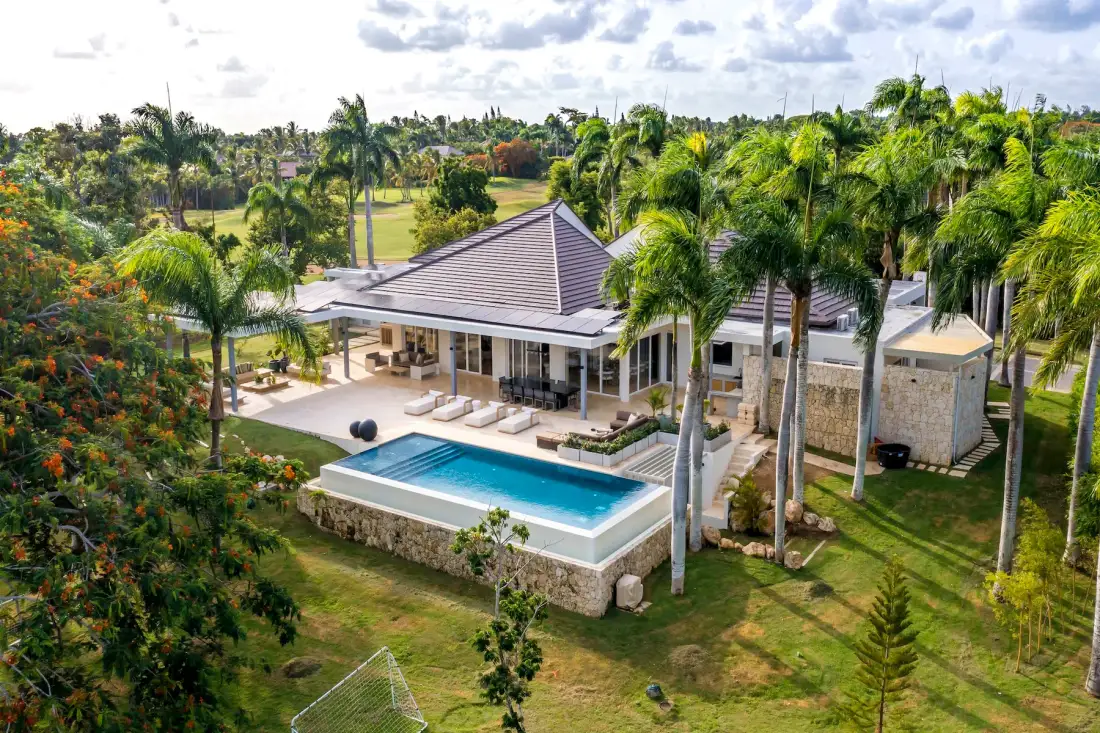 Vista aérea de una villa tropical con piscina y palmeras.