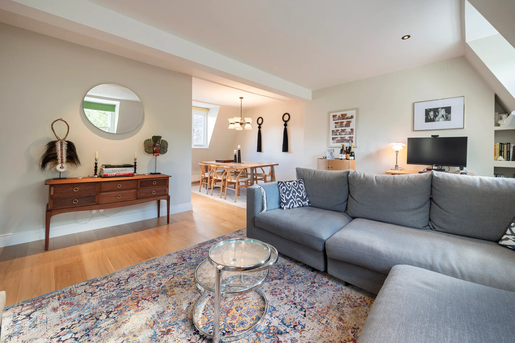 A bright living room with gray seating and an adjoining dining area.