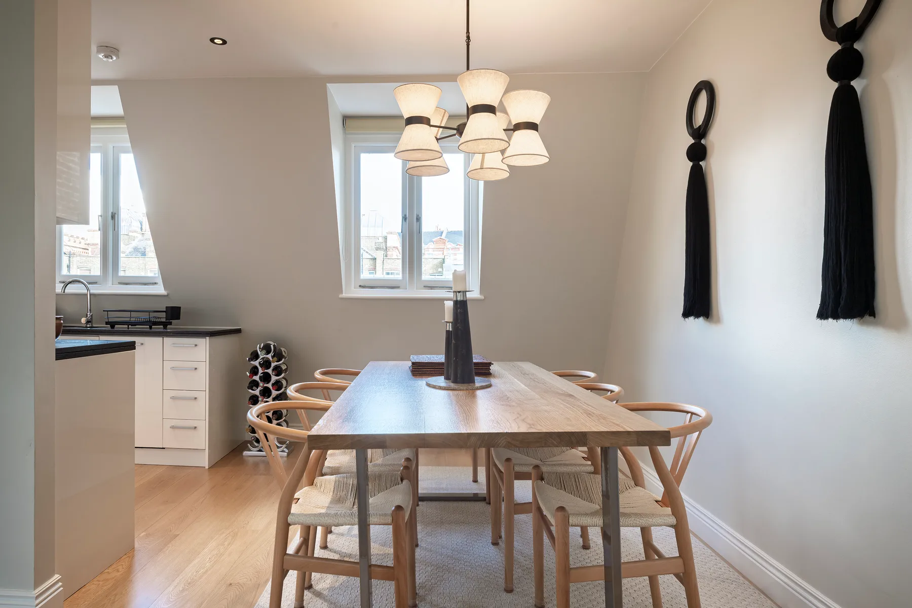 A dining area with a wooden table and chairs beneath pendant lights.