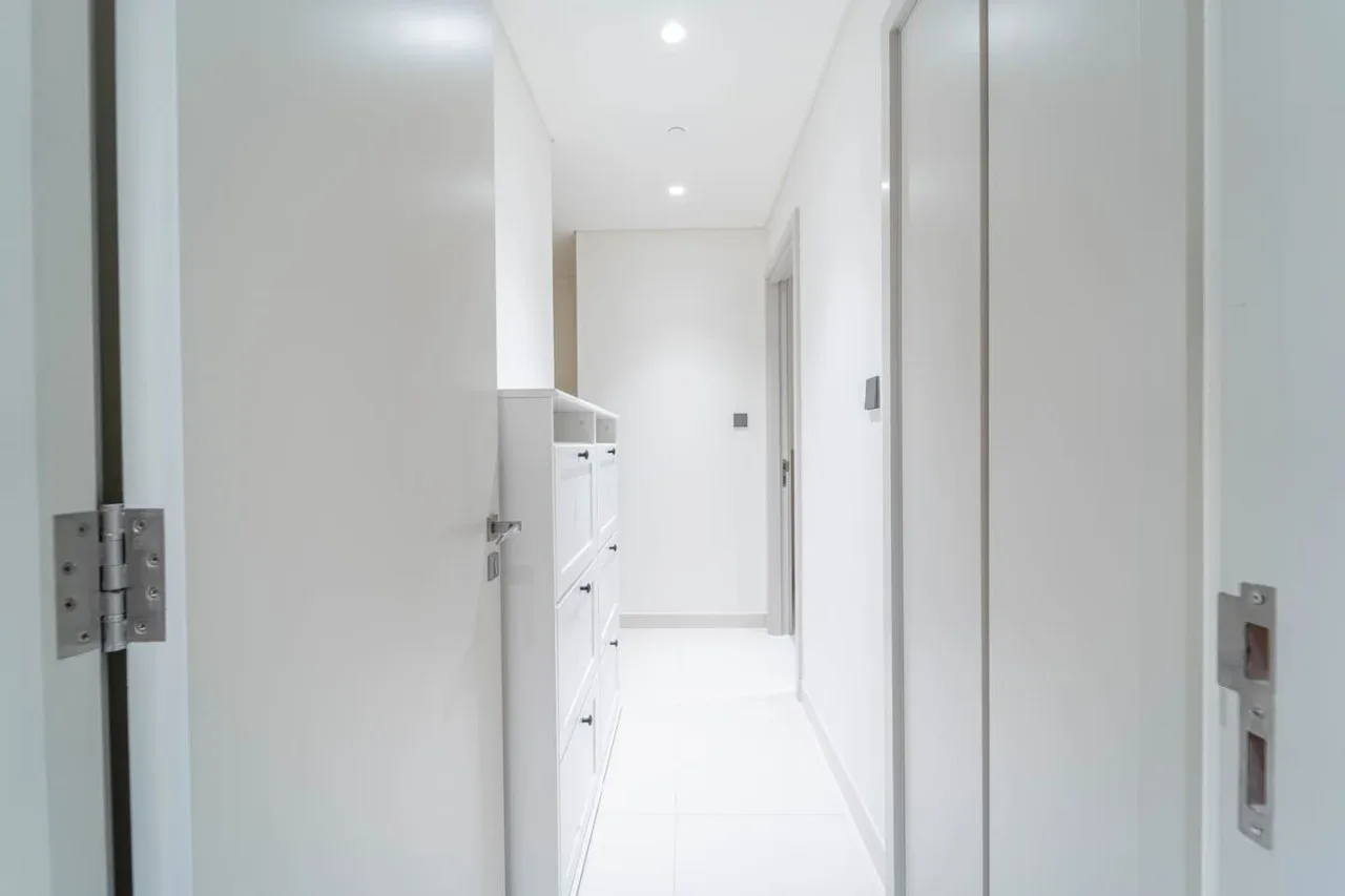 A bright white hallway with built-in cabinets and several doorways.