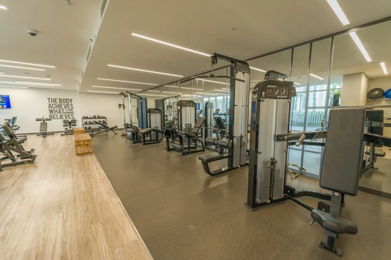 A gym with exercise machines and a mirrored wall.