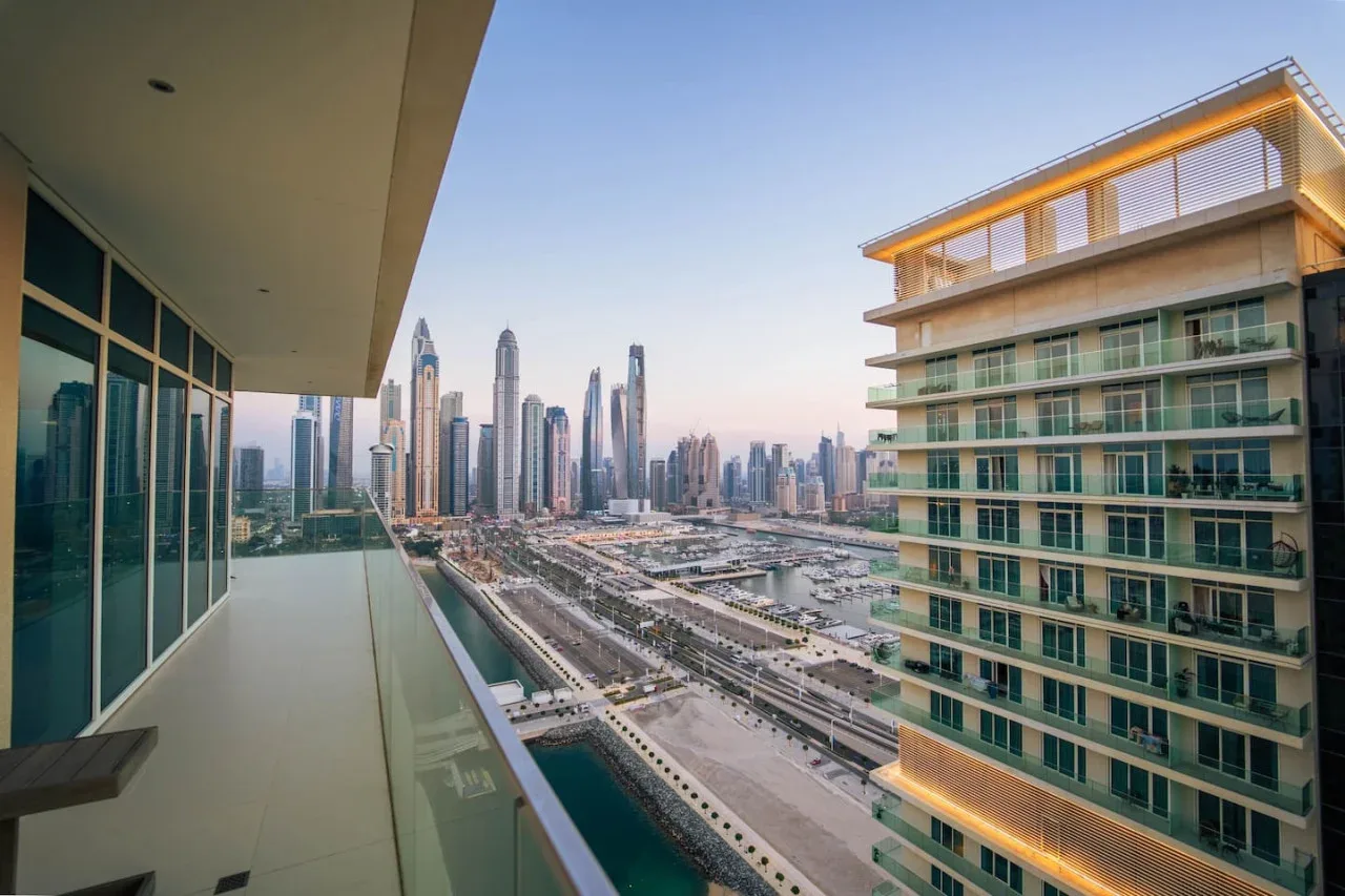 A balcony overlooks a city skyline, with a modern building nearby.
