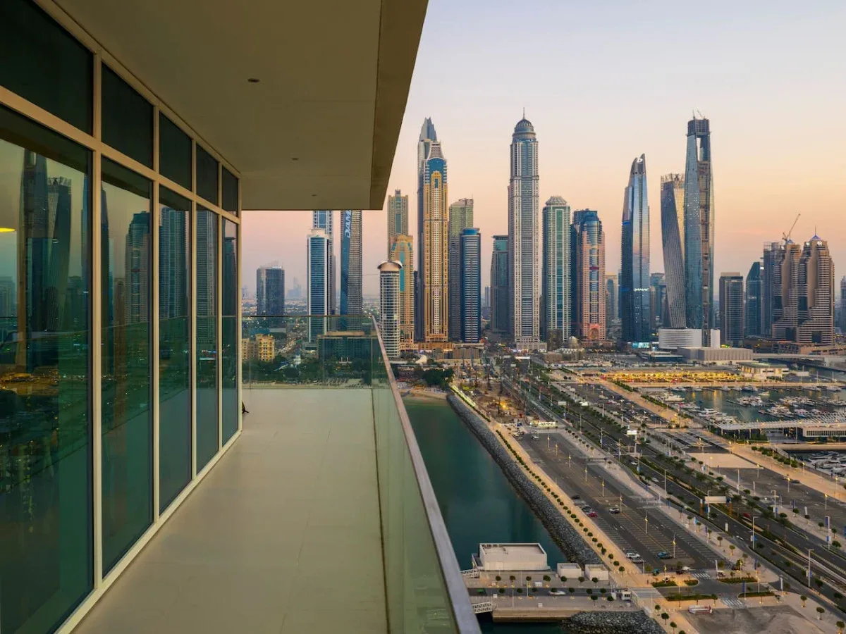 A balcony overlooks a city skyline and a canal at dusk.