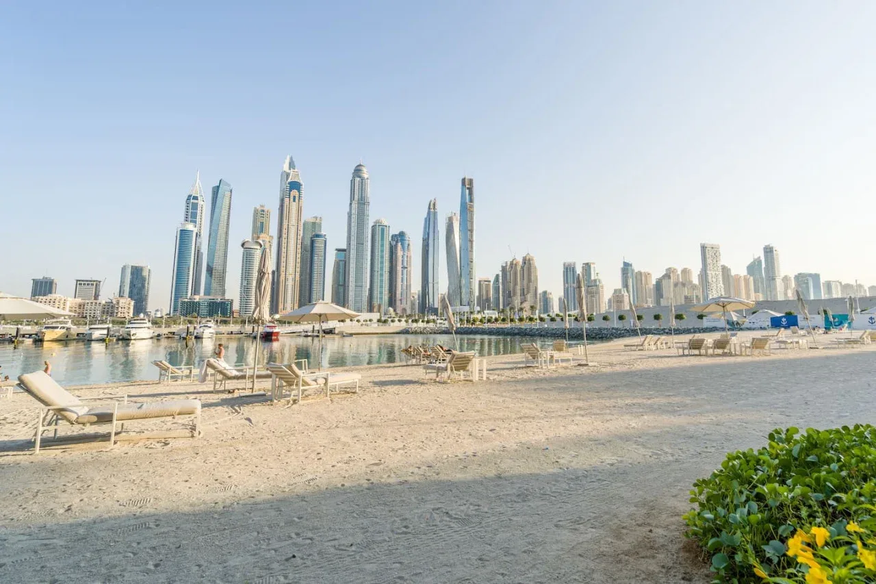 A sandy waterfront beach faces a city skyline across the water.
