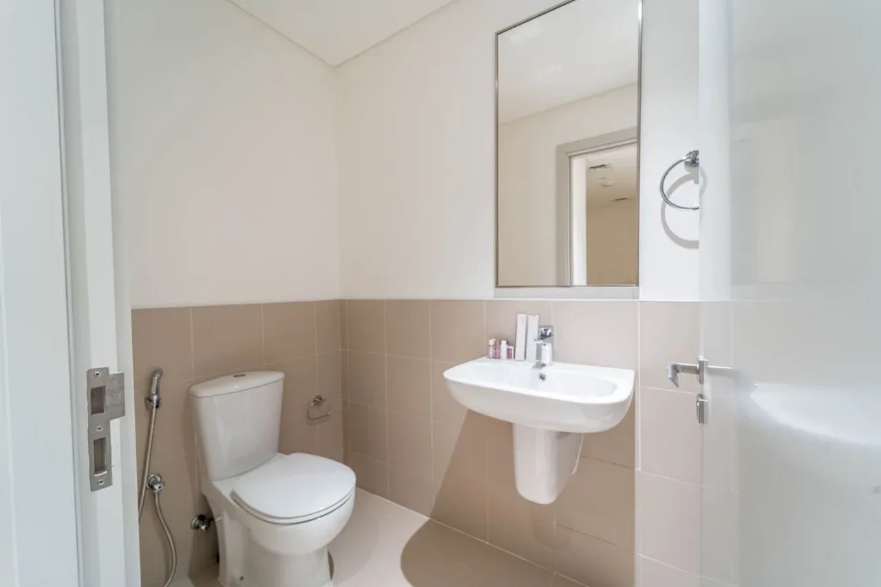 A bright bathroom with a toilet, sink, and wall mirror.