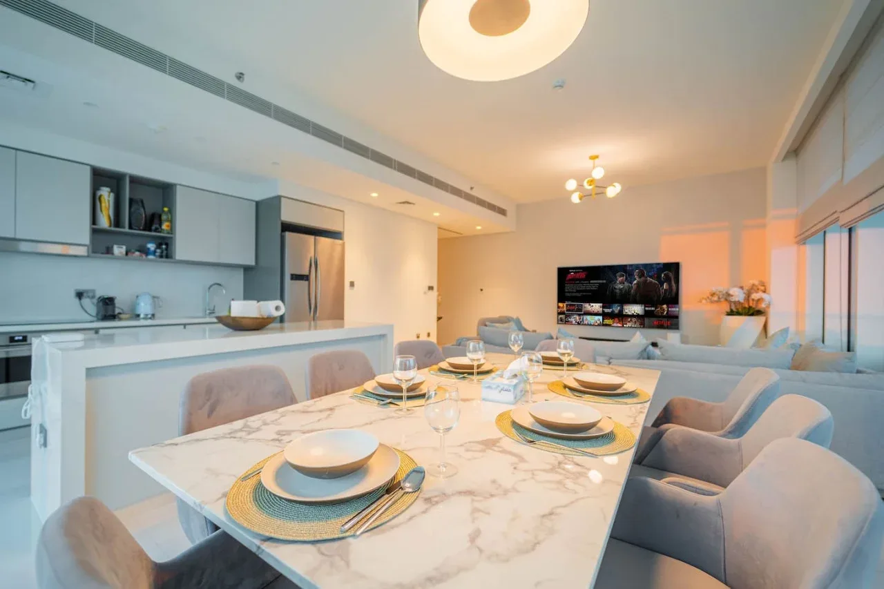 A bright dining area with a set table beside an open kitchen.