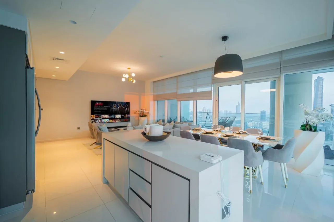 A modern kitchen and dining area with a large island and windows overlooking the city.