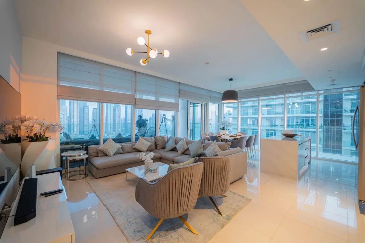 A bright living room with seating arranged beside floor-to-ceiling windows.