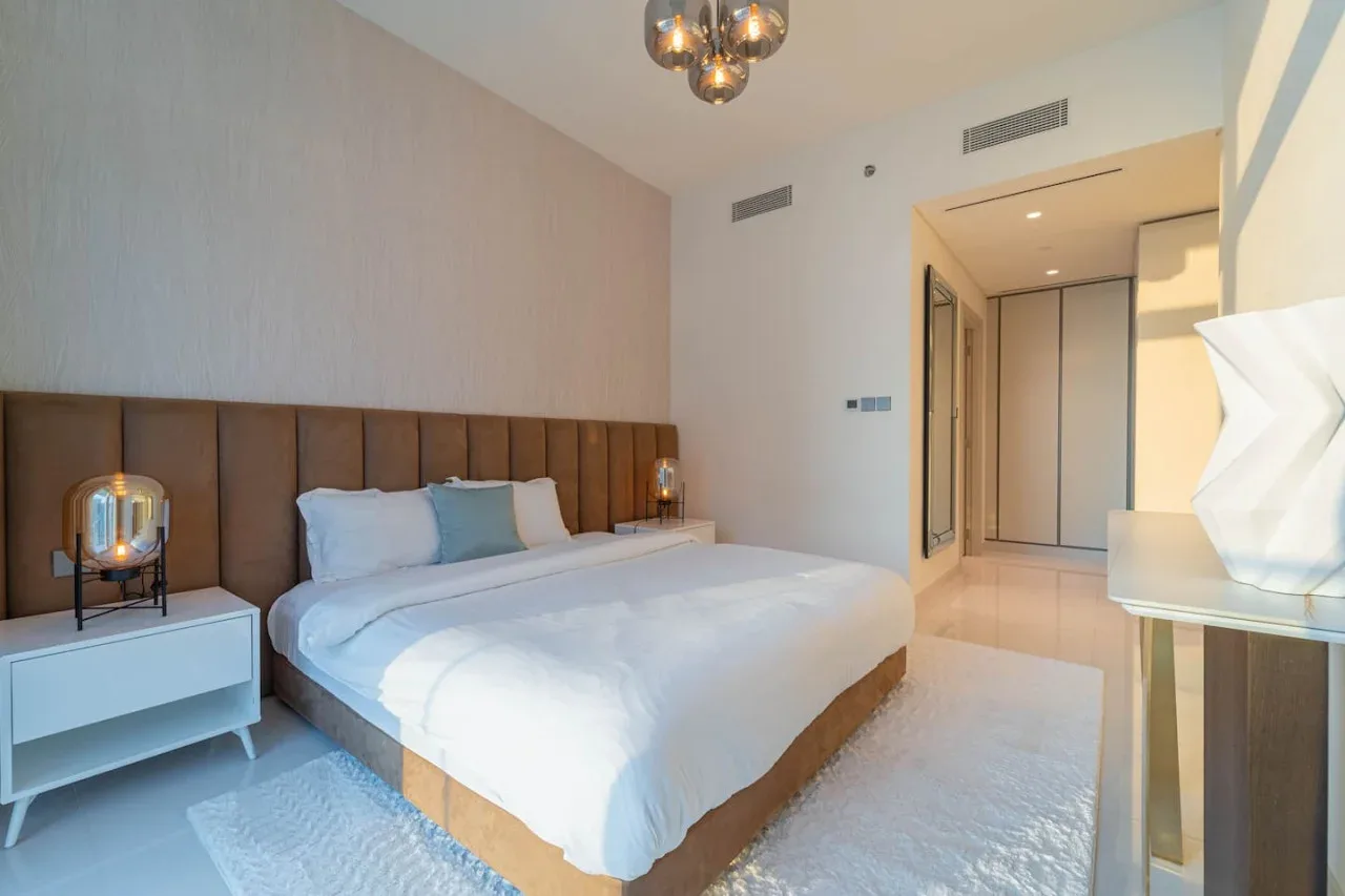 A bedroom with a neatly made bed and bedside tables.