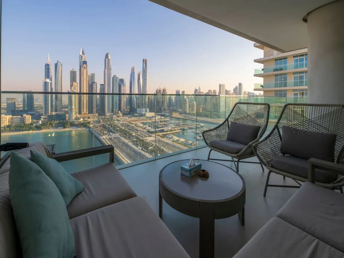 A balcony seating area overlooks a waterfront city skyline.