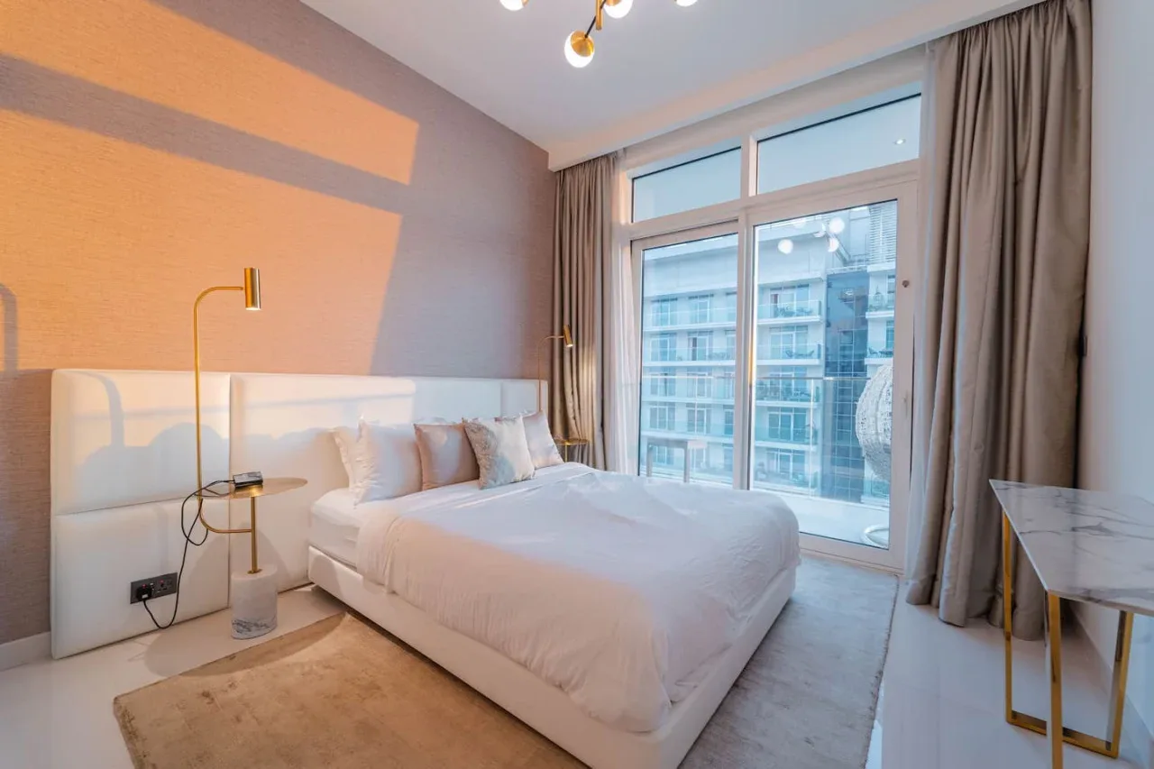 A bedroom with a bed beside tall windows and curtains.