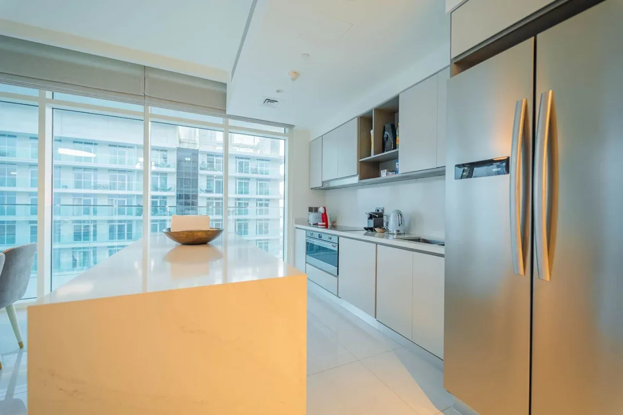 A modern kitchen with an island and large windows.
