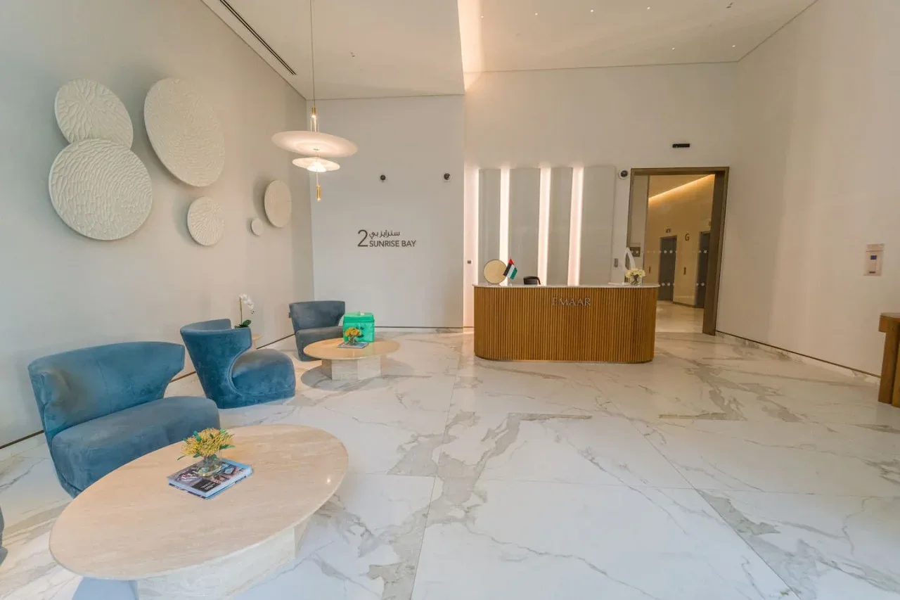 A bright reception lobby with a curved wooden desk and blue seating.