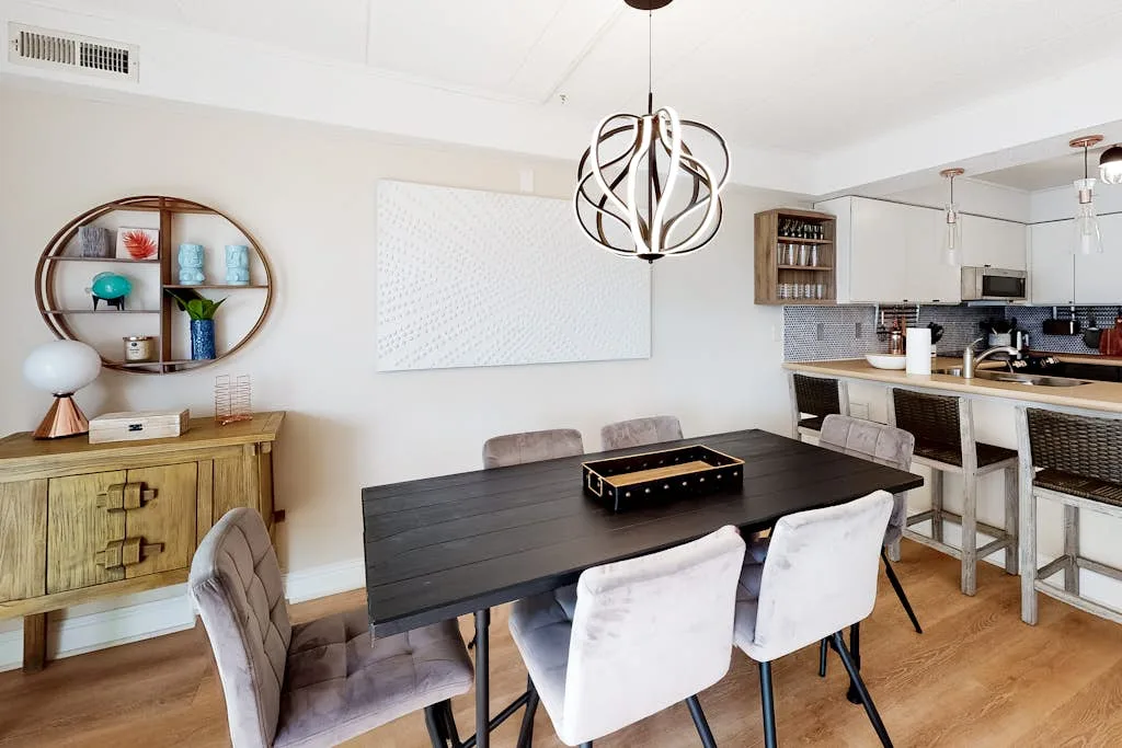Comedor con una mesa oscura y una cocina abierta al fondo.