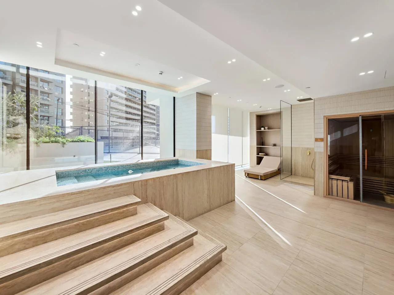 Un luminoso espacio de spa interior con piscina elevada y sauna.