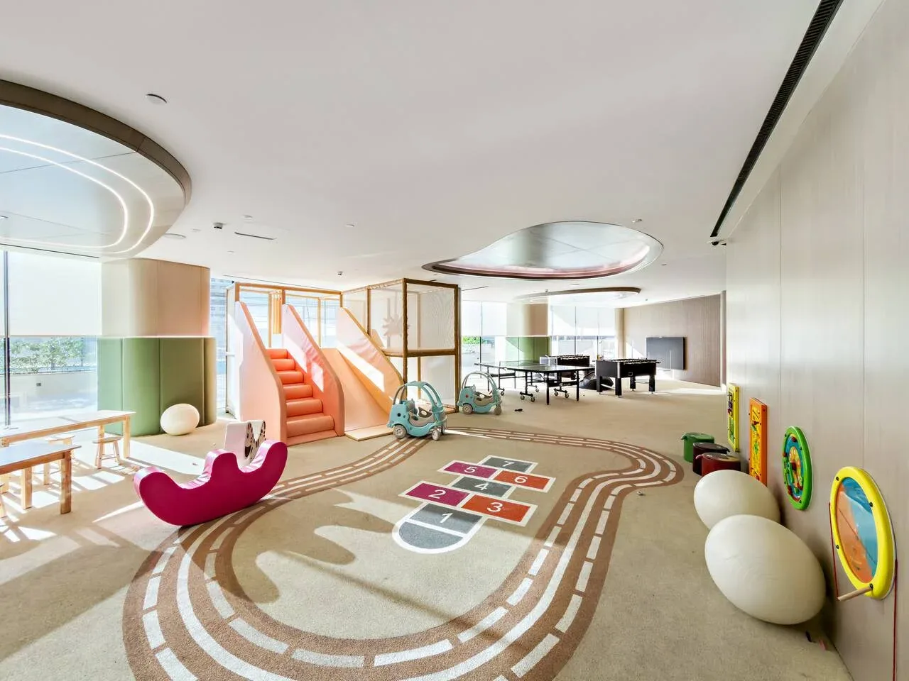 Una luminosa zona de juegos interior tiene un recorrido colorido en el suelo y juegos.