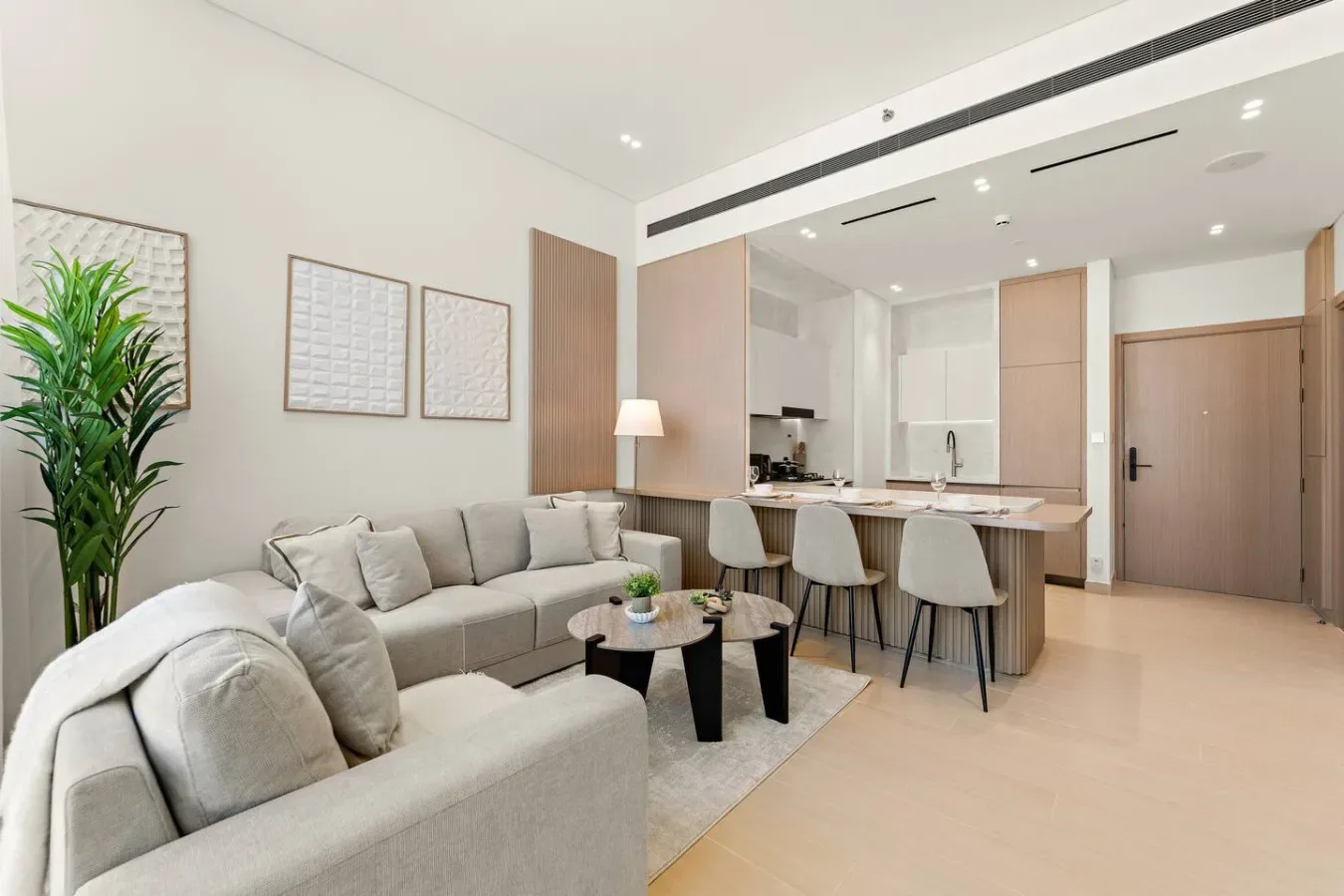 Una sala luminosa con asientos junto a una cocina abierta y una barra de comedor.